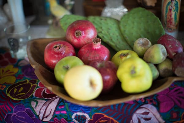 maçãs, pêras e nopales numa tigela de madeira sobre um dia de muertos offrenda