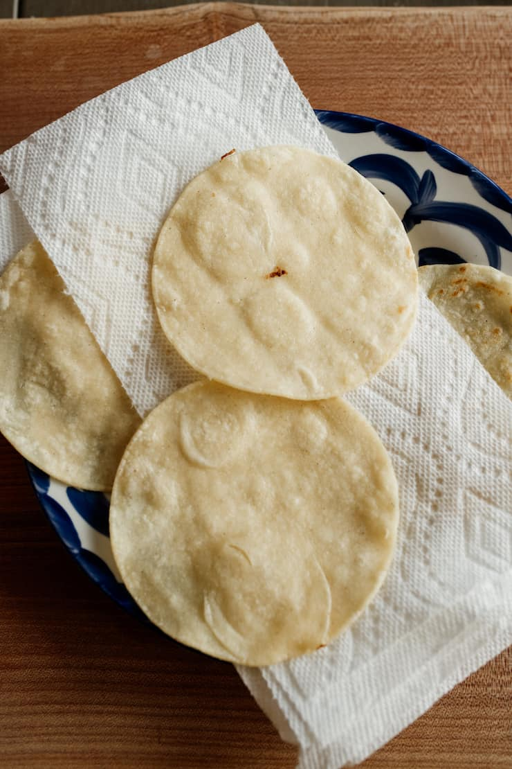 tortilhas de milho levemente fritas a escorrer num prato forrado com papel toalha