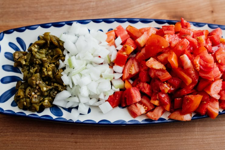 tomates em cubos, cebolas e pimentão verde assado em prato oblongo azul e branco