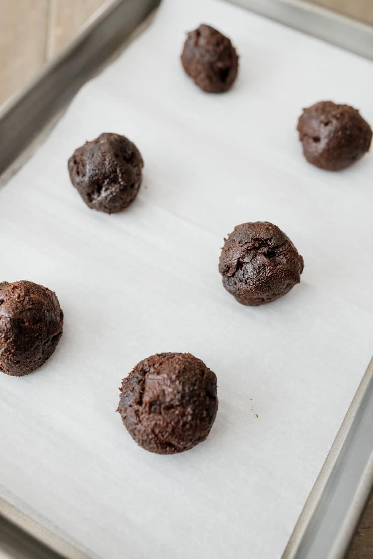 bolas de massa de biscoito de chocolate em uma assadeira forrada com pergaminho