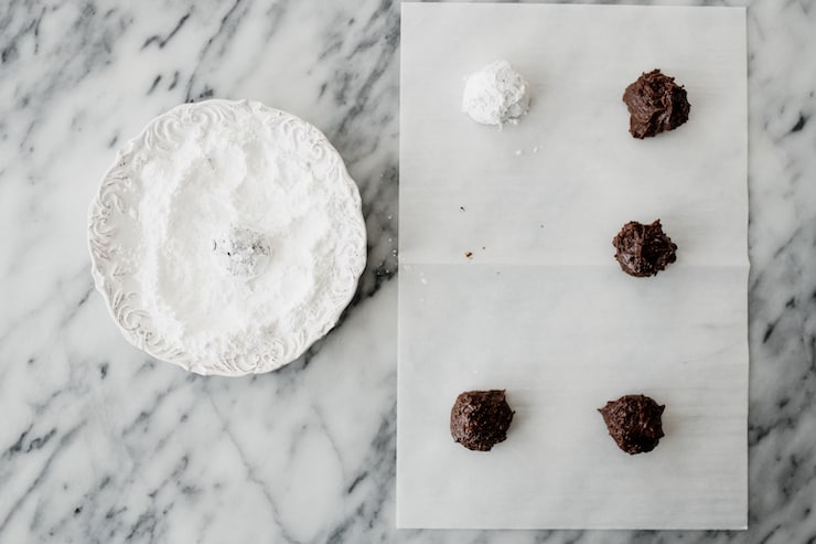 folha de pergaminho com biscoitos enrolados, um dos quais foi revestido com açúcar em pó