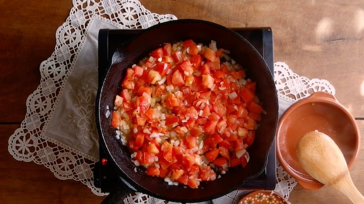 tomates e cebolas salteados numa frigideira para sopa de almôndegas