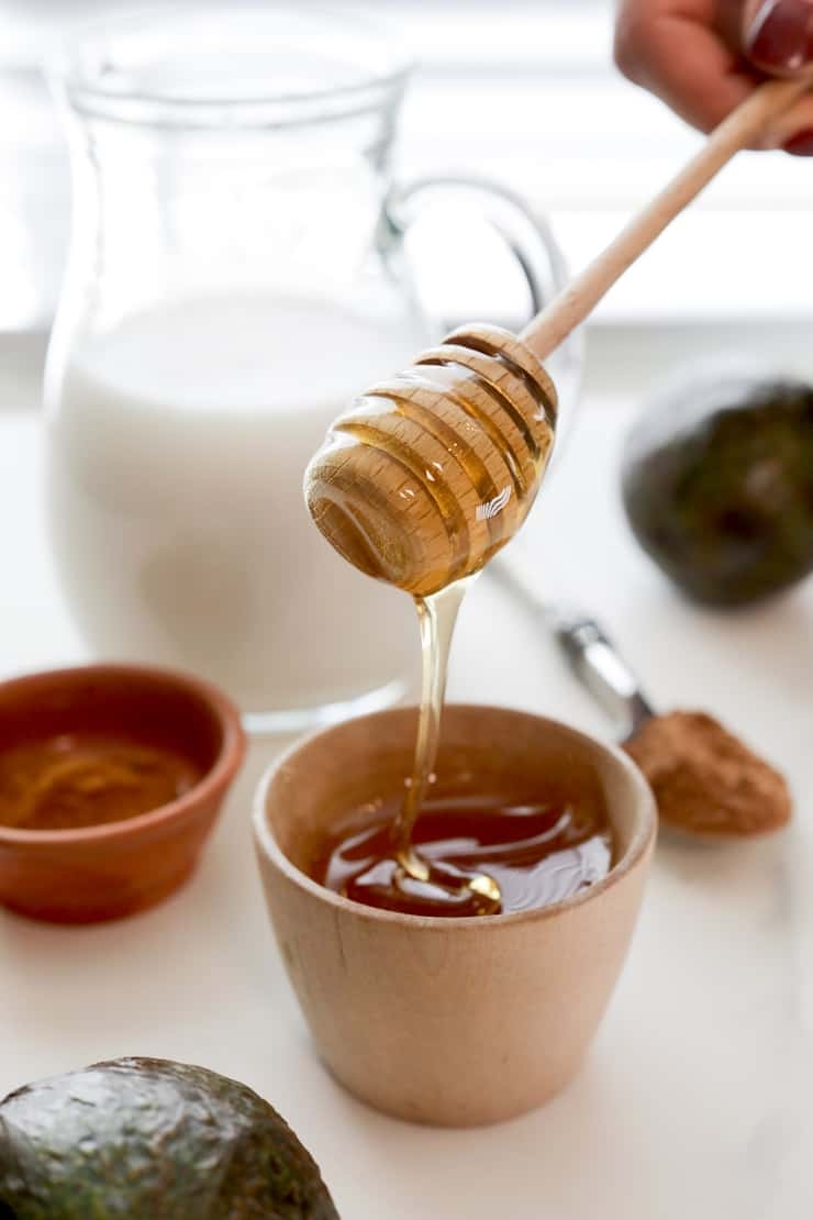 Ursa de mel de madeira com mel a chuviscar de volta para dentro de uma tigela