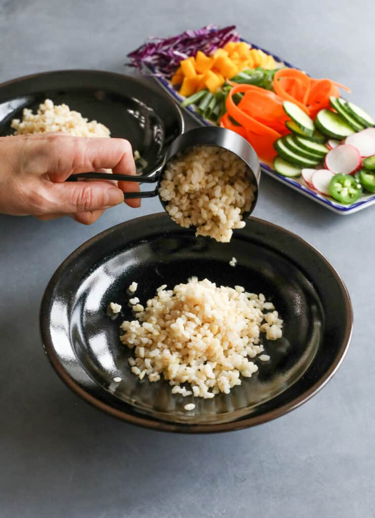 Medindo manualmente o arroz marrom em uma tigela preta