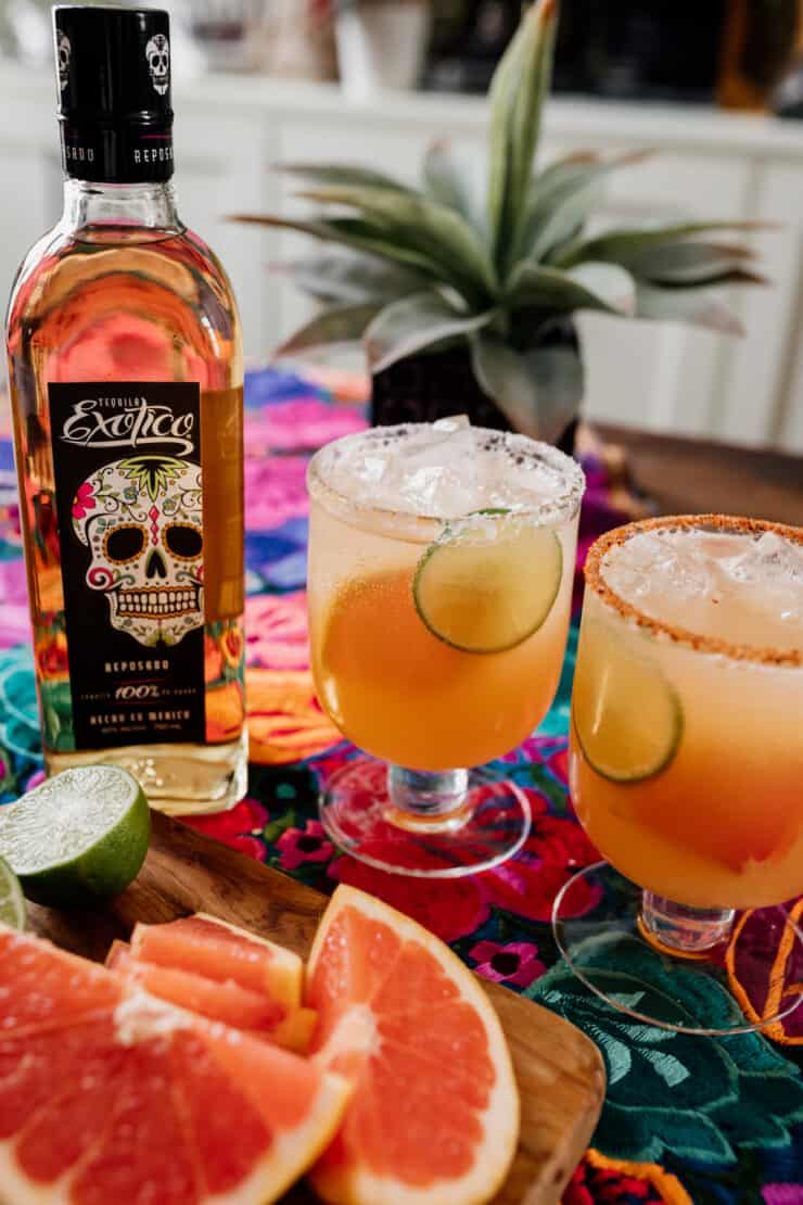 dois cocktails Paloma cintilantes com garrafa de Tequila Exotico ao fundo