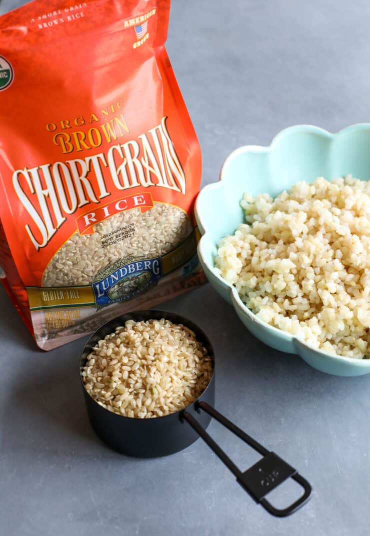 saco de arroz de grão curto castanho lundberg com uma chávena de medida de arroz seco ao lado de uma tigela de arroz cozido