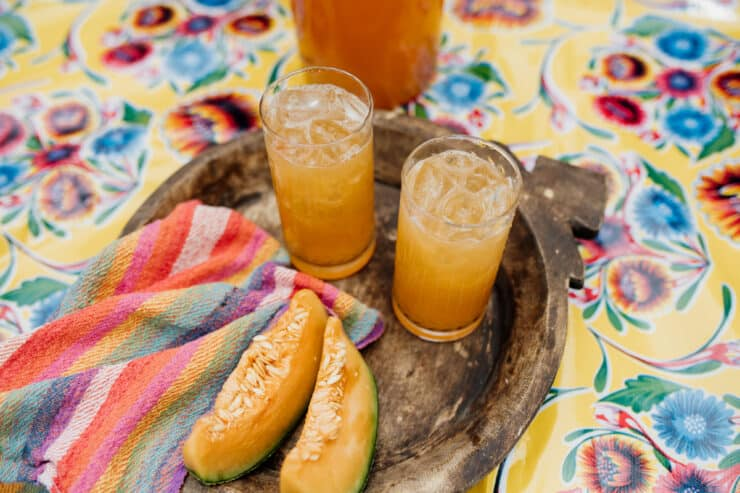 Água de Melão sobre bandeja de madeira com guardanapo colorido listrado e toalha de mesa mexicana floral amarela