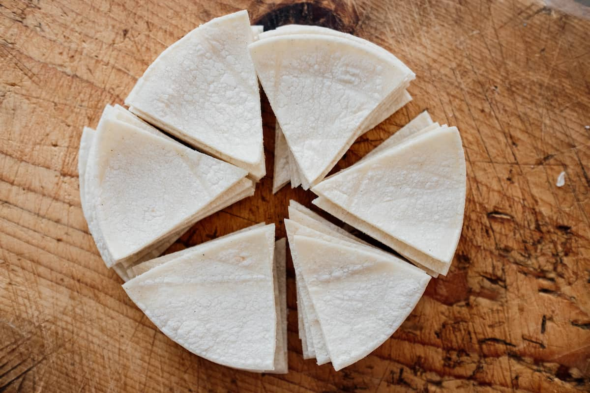 tortilla de milho estragada cortada em triângulos sobre uma tábua de madeira para fazer chilaquiles