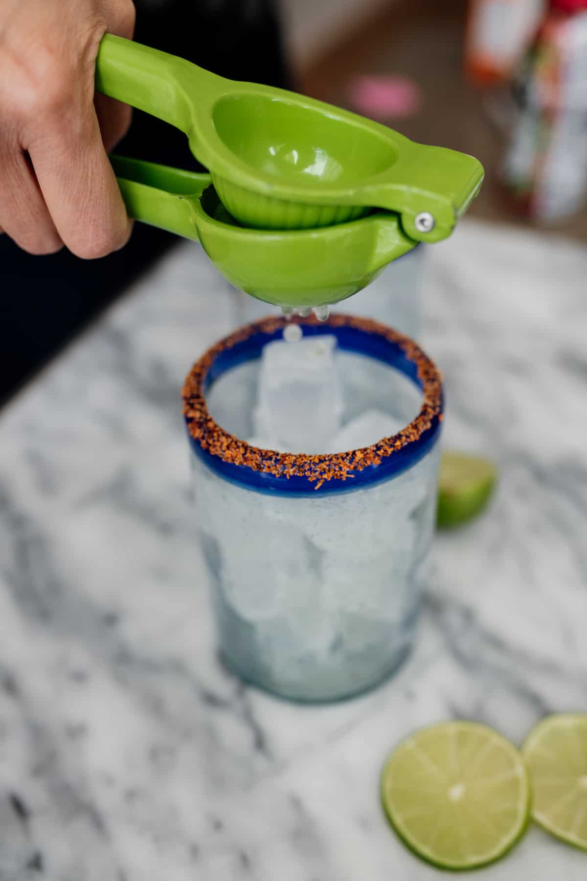 espremedor de lima com sumo de lima fresca num copo de tajin com gelo para um cocktail de cerveja