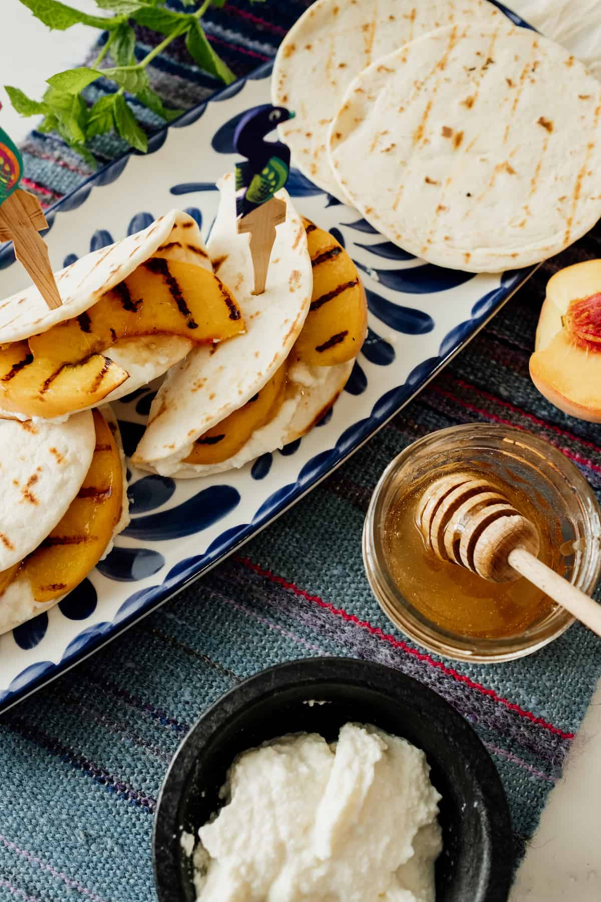 Mini Tortilhas com Queijo Ricotta e Pêssego Grelhado em bandeja mexicana azul e branca e palito de madeira do México