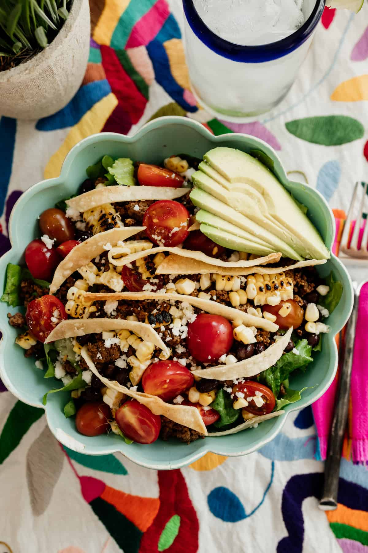 Uma salada de Taco saudável, servida numa tigela turquesa guarnecida com coberturas coloridas num corredor Otomi colorido.