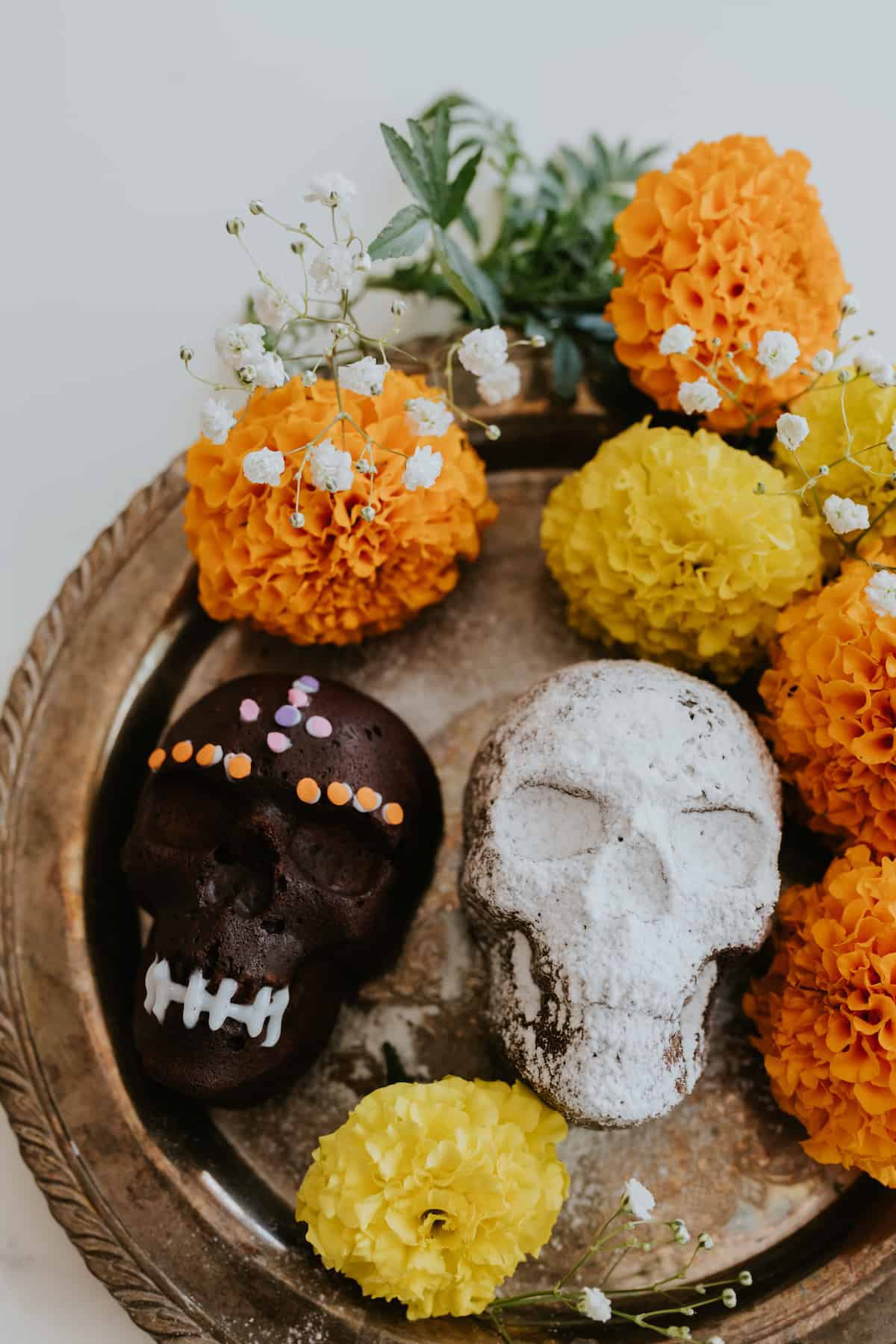 Bolos de Caveira de Chocolate decorados para Dia de los Muertos rodeados de calêndulas