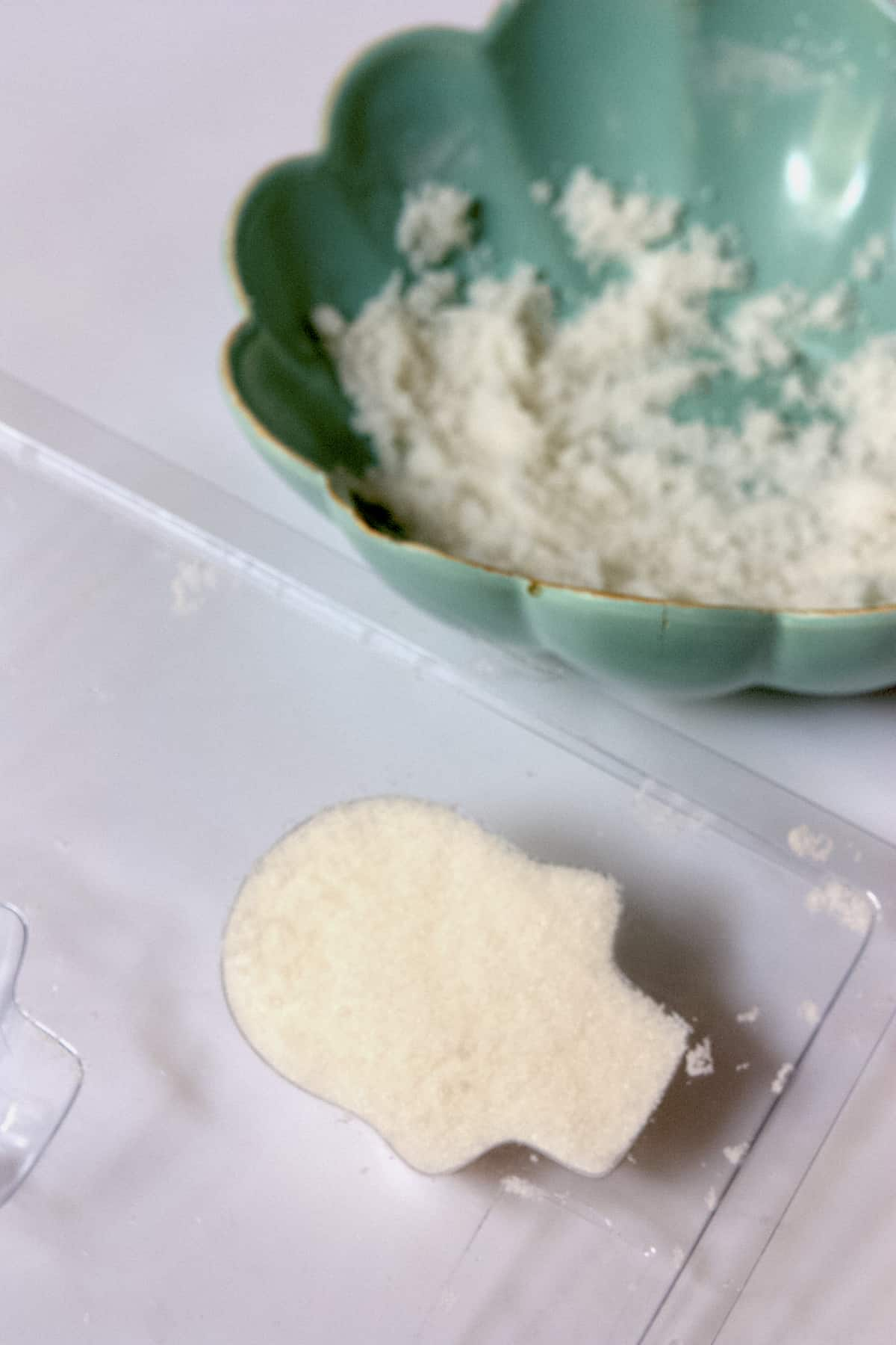 a mistura de açúcar para criar estes crânios do Dia do Açúcar Morto num molde de plástico do crânio