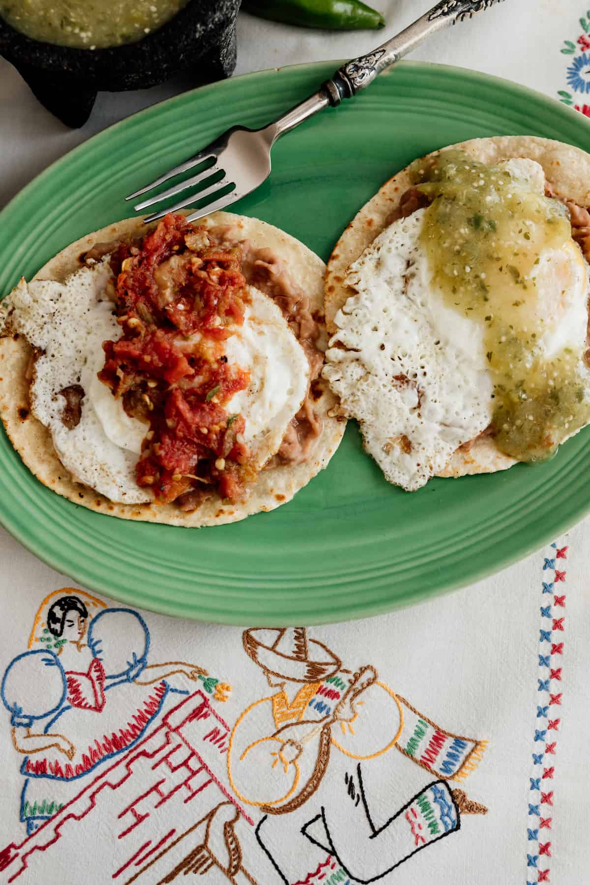 prato verde com Huevos Divorciados -- tortilhas de milho cobertas com feijão frito, ovos e salsa vermelha e verde