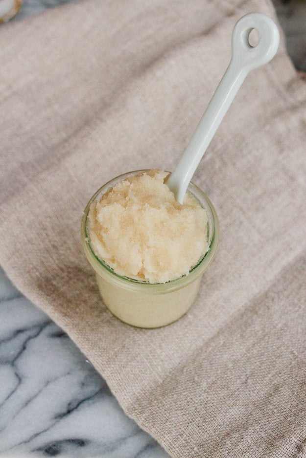 Pequeno frasco de açúcar de coco caseiro chicoteado com uma colher de sopa a sair do frasco.