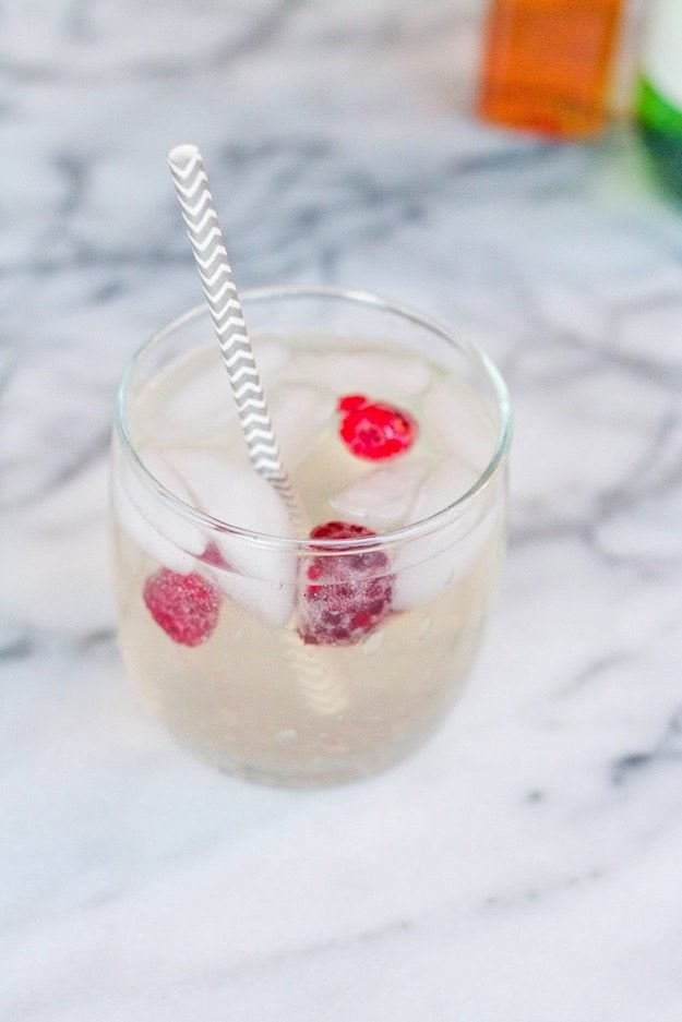 Vinagre de lima de maçã de flor de sabugueiro cintilante Mocktail em vidro transparente sobre bancada de mármore branco.