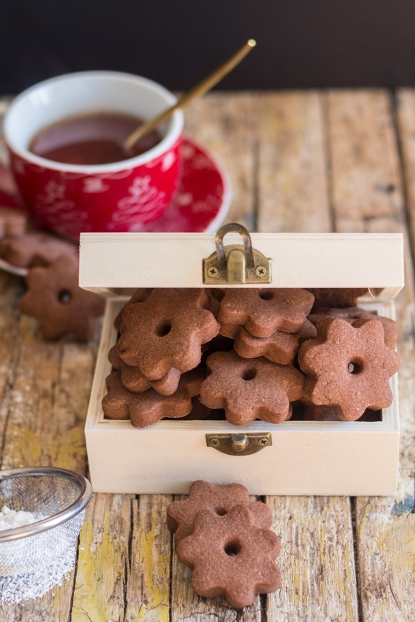biscoitos canestrelli de chocolate em uma caixa de madeira com uma xícara de chá