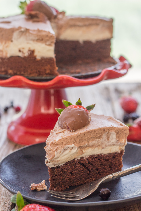 bolo duplo de mousse de chocolate em uma banca de bolo com uma fatia em um prato