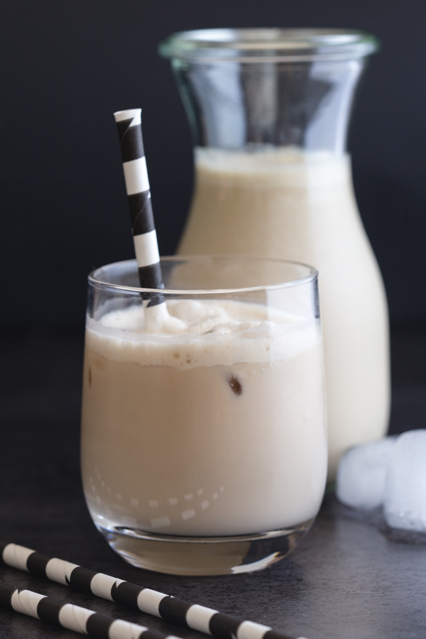 café gelado num copo com uma palhinha preta e branca e um jarro