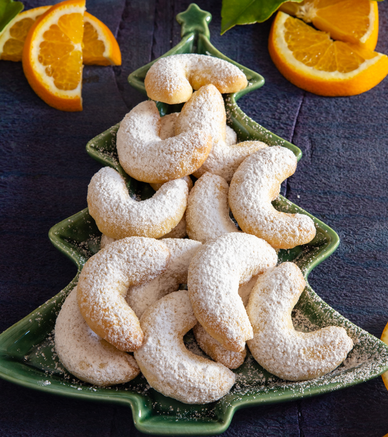 biscoitos em forma de lua crescente de laranja num prato de árvore verde com fatias de laranja