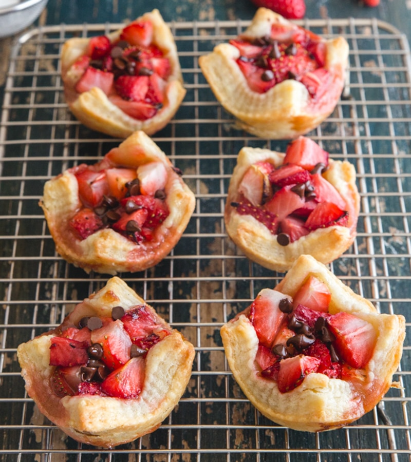 tartes de morango em uma grade de arame com 3 morangos frescos e açúcar em pó