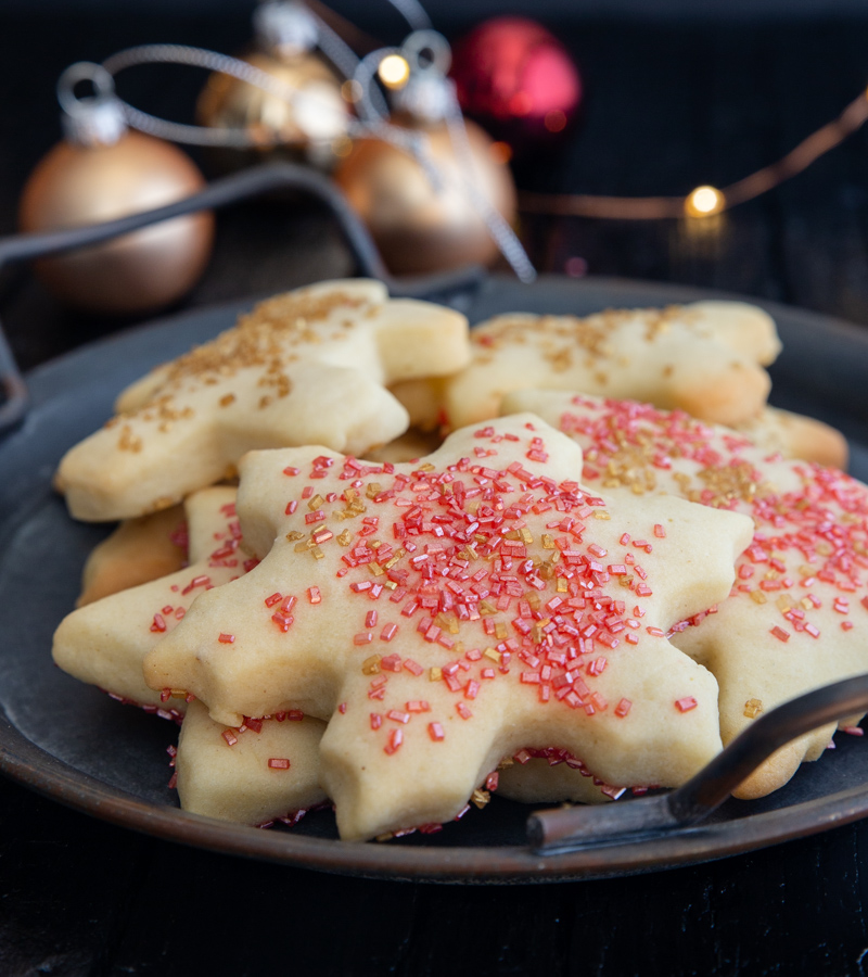biscoitos de açúcar num prato preto com luzes de fadas e bolas de árvore de Natal