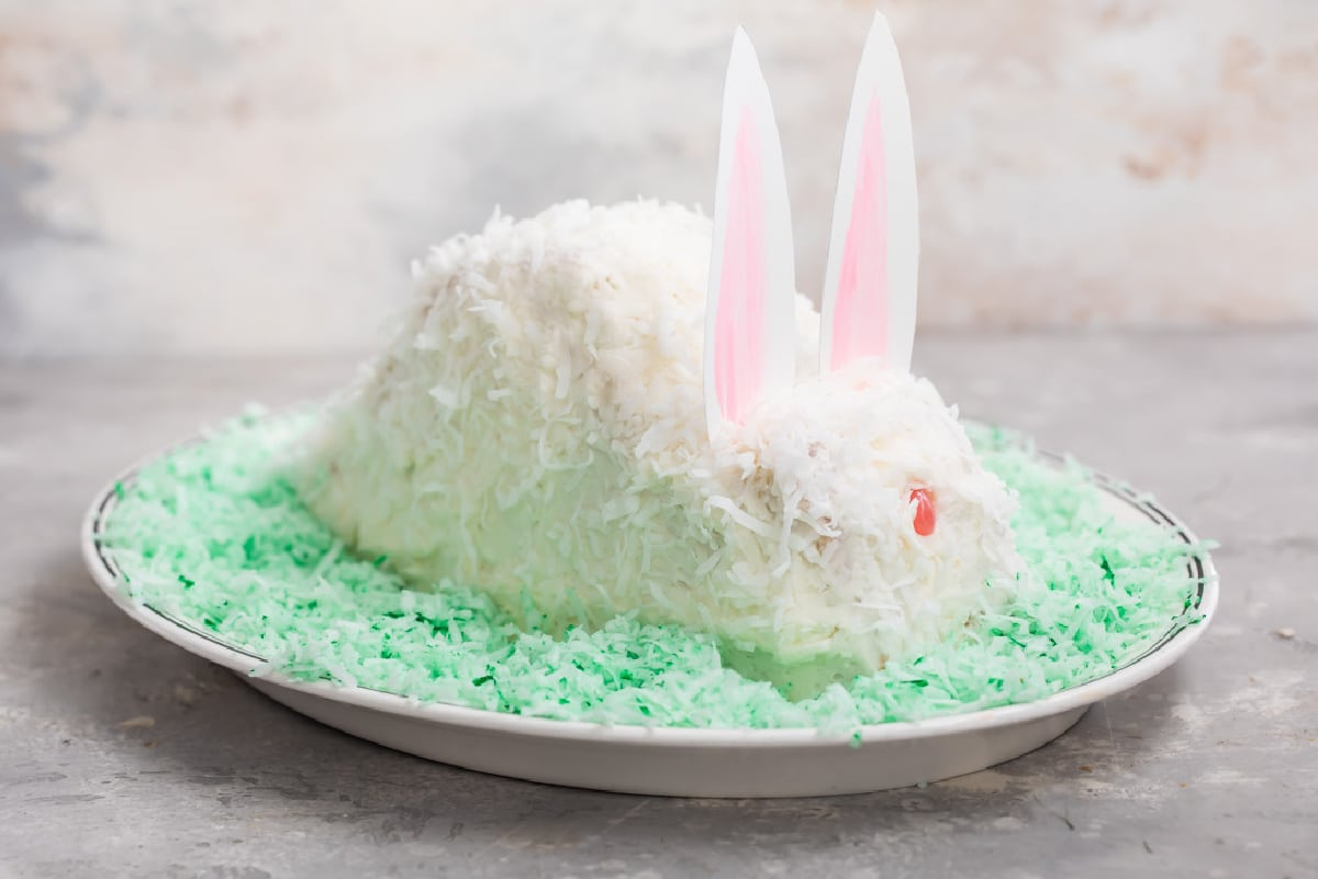 Um bolo de coelho sobre uma cama de coco verde num prato oval.