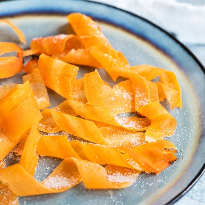 Cachos de cenoura cristalizados em um prato azul.