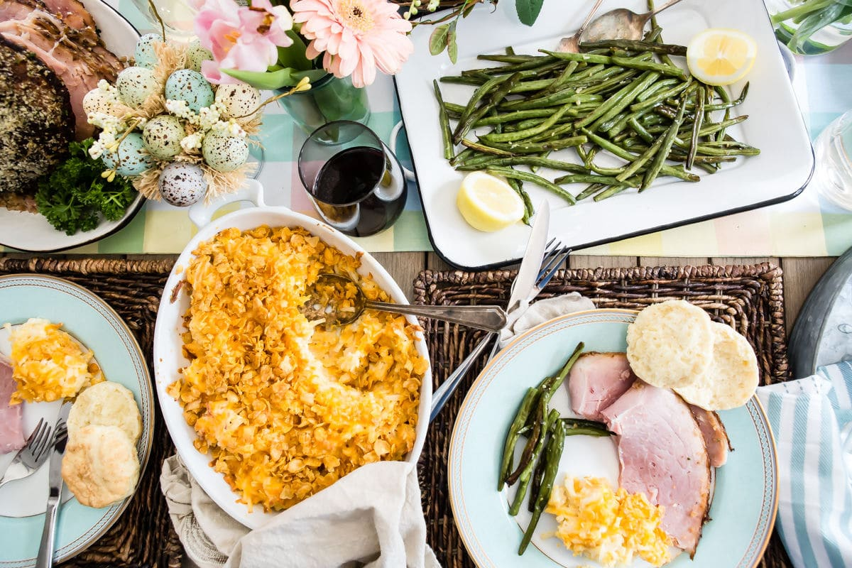 Um conjunto de mesa para a Páscoa com presunto assado, batatas com vieiras, feijão verde assado e bolachas caseiras.