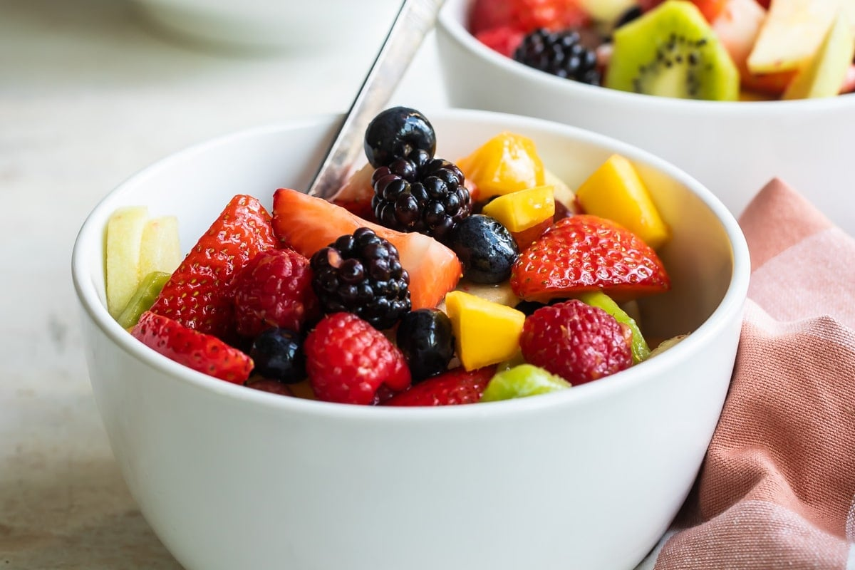 Salada de frutas em uma pequena tigela branca.