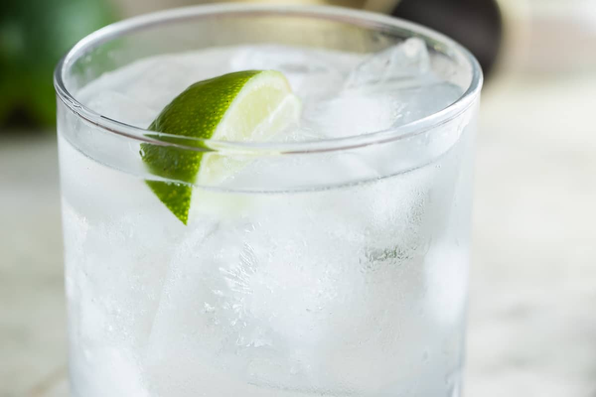 Um cocktail de gin e tónico num copo transparente.