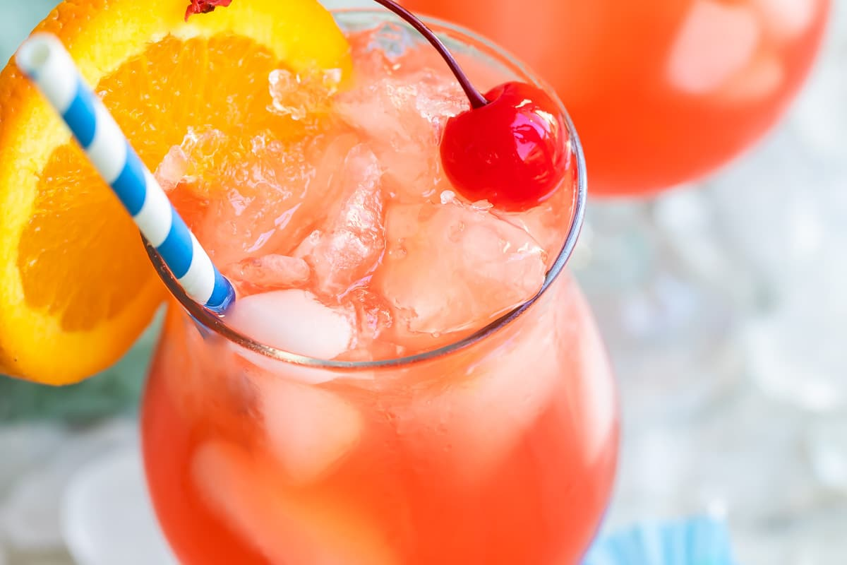 Um cocktail de furacões com uma fatia cor-de-laranja guarnecida com uma palha listrada azul e branca.