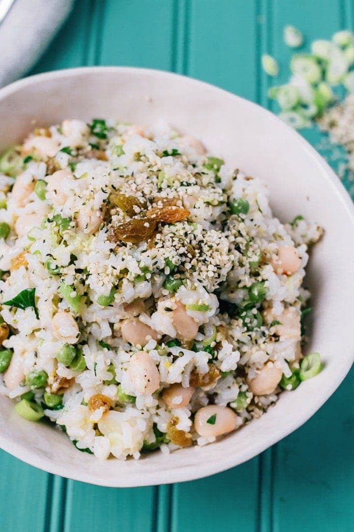 Salada de arroz de lemónio com feijão, cebolinha verde e sementes de sésamo numa mesa de marmelada.