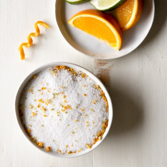 Sal Margarita em um prato branco com fatias de uma laranja em outro prato branco.