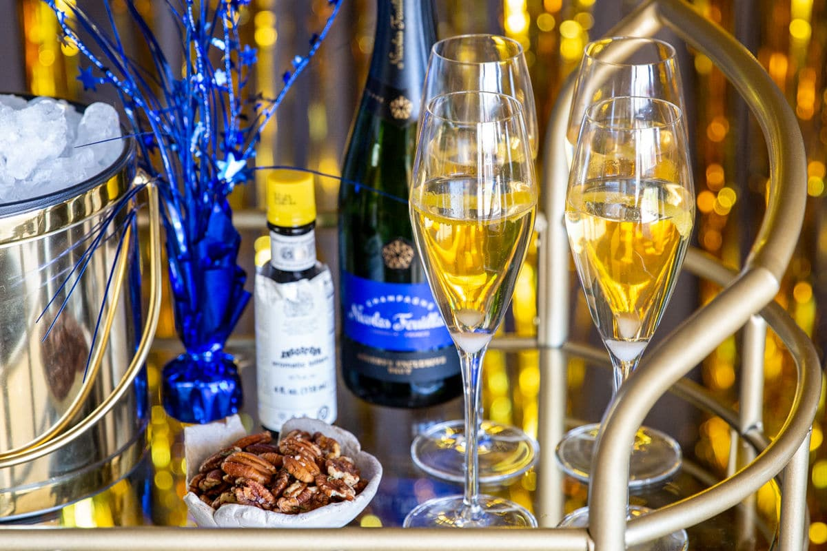 Um carrinho de bar com cocktails de champanhe, nozes e decorações de Ano Novo.