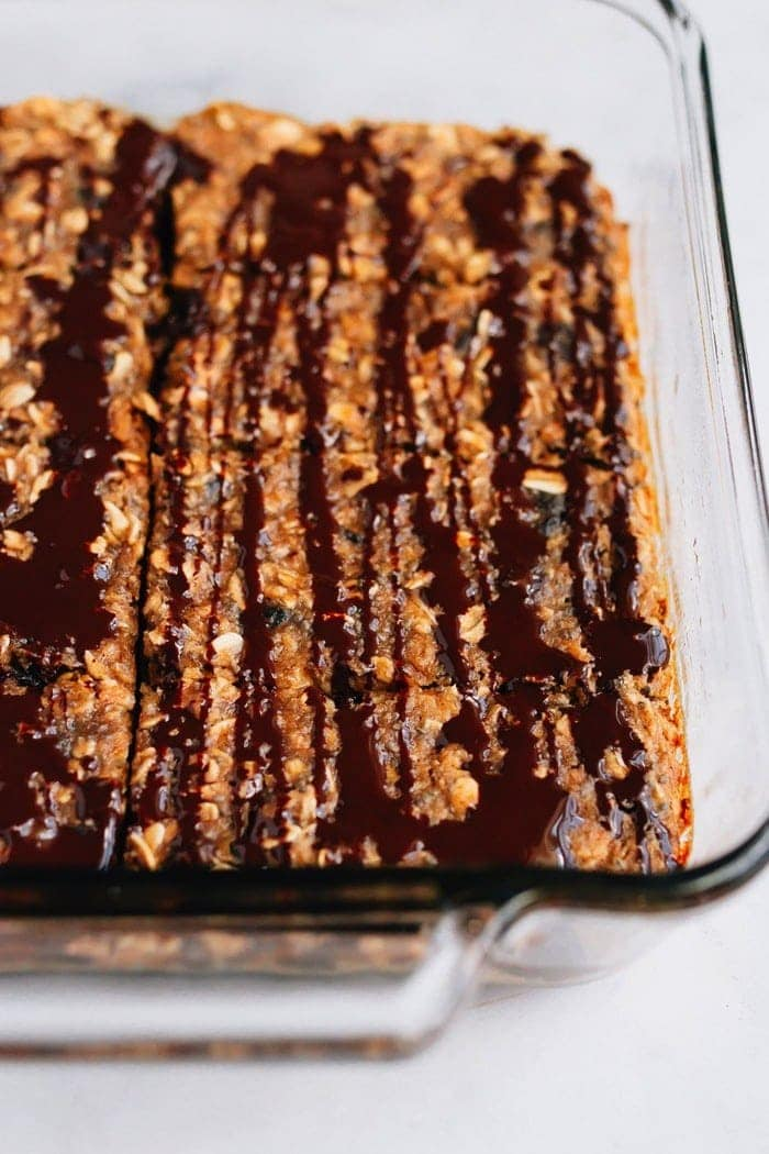 Tabuleiro cheio de barras de proteína de passas de aveia com chuvisco de chocolate preto.