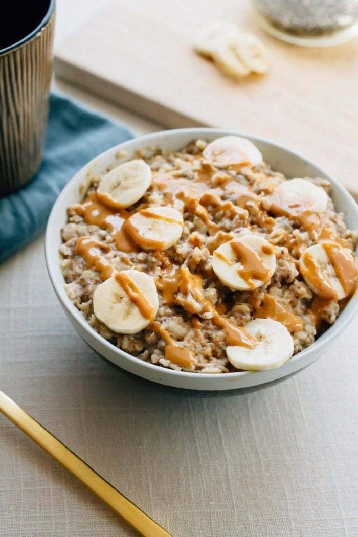 Tigela de aveia com banana picada e manteiga de amendoim salpicada no topo.