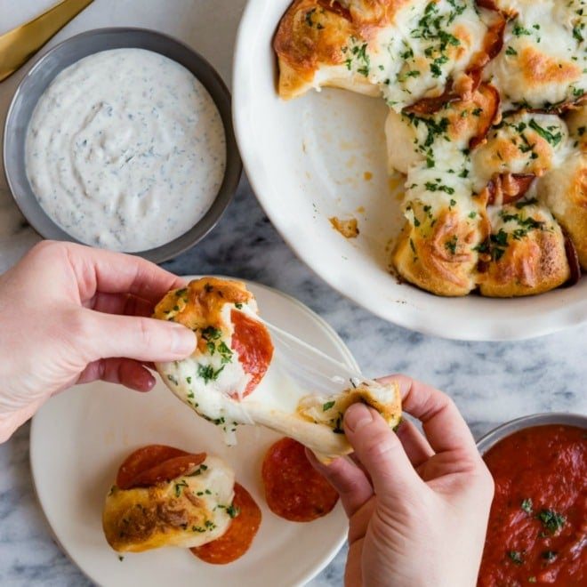 Mordidas de pizza de Pepperoni a serem arrancadas num prato branco.