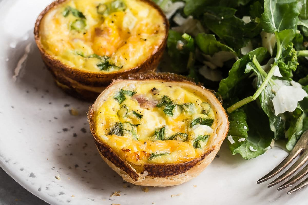 Queques de quiche em um prato com salada de rúcula.