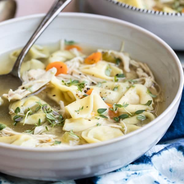 Sopa de tortellini de frango slow cooker em uma tigela branca.