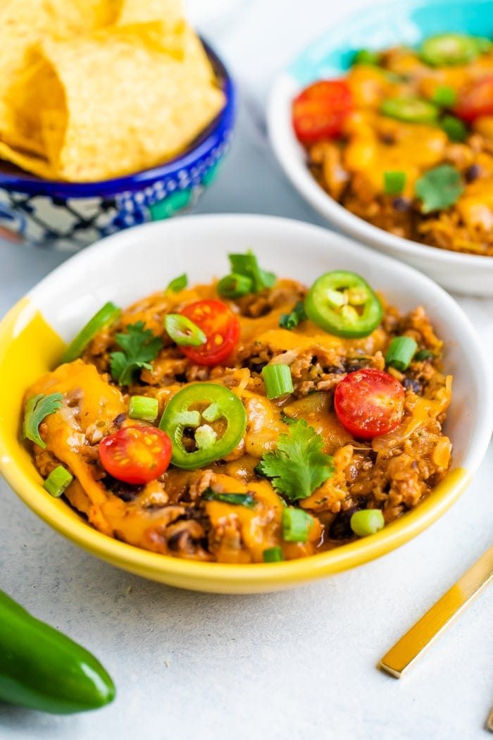 Tigela de taco de esparguete com baixo teor de esparguete com queijo, coberta com legumes.