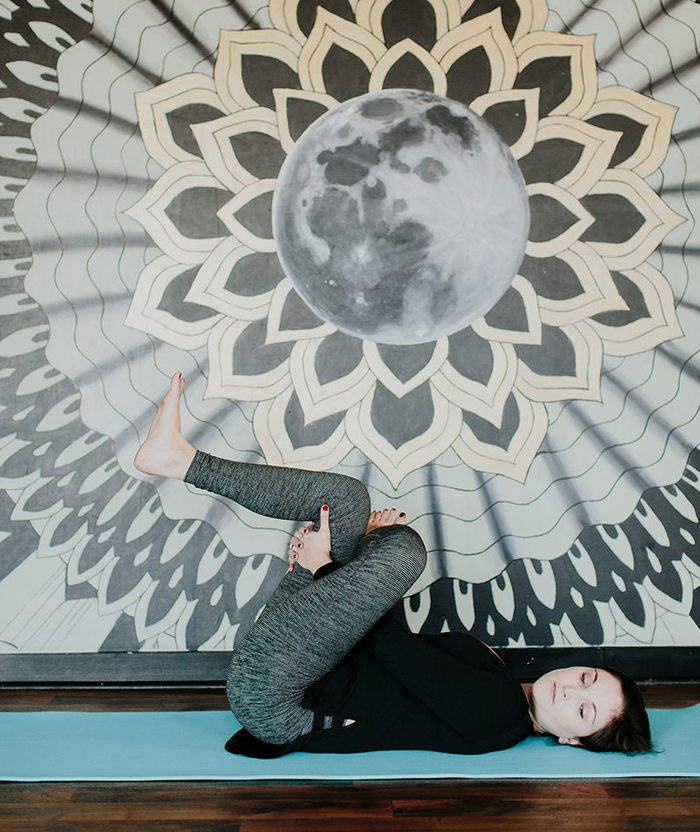 Mulher a esticar pernas em tapete de ioga.