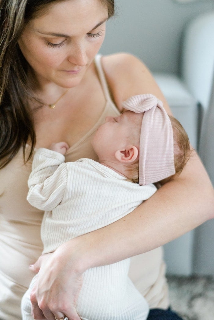 Mulher com bebé recém-nascido. O bebé tem uma faixa na cabeça.