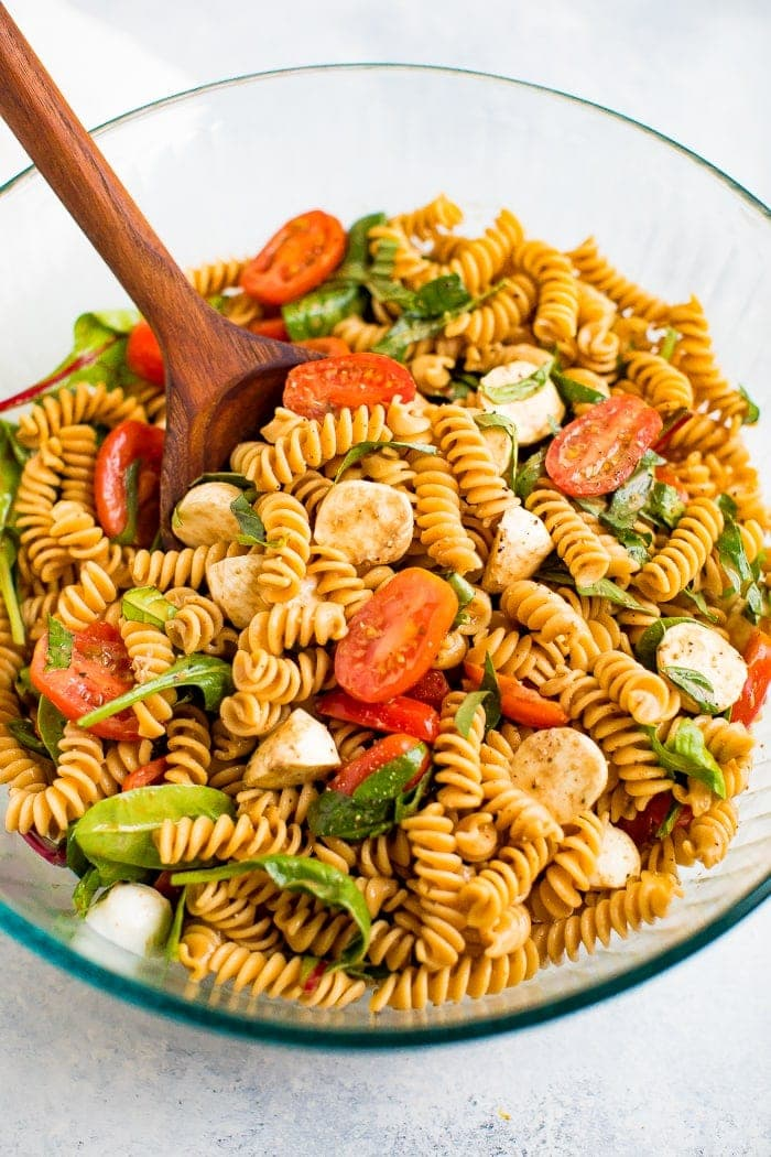 Taça para servir com salada de massa caprese sem glúten com tomate, mozzarella, manjericão e um vinagrete balsâmico.