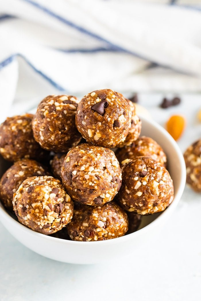 Tigela branca cheia de bolas energéticas de chocolate com pepitas de coco.