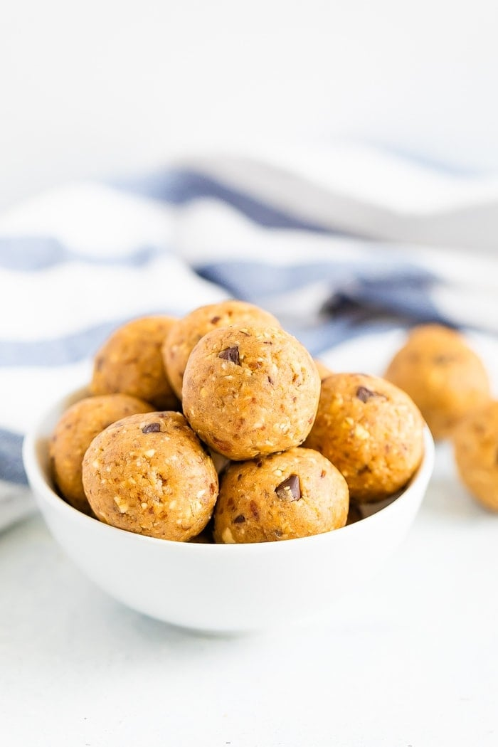 Tigela branca cheia de bolinhas de massa de biscoito com pedaços de chocolate.