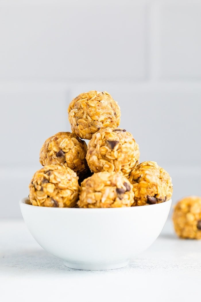 Tigela branca cheia de bolas energéticas de chocolate com pepitas de manteiga de amendoim.