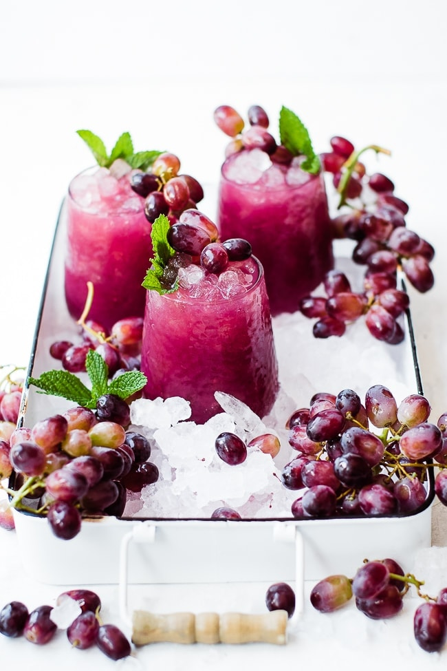 três copos de sumo de uva, gelo e uvas