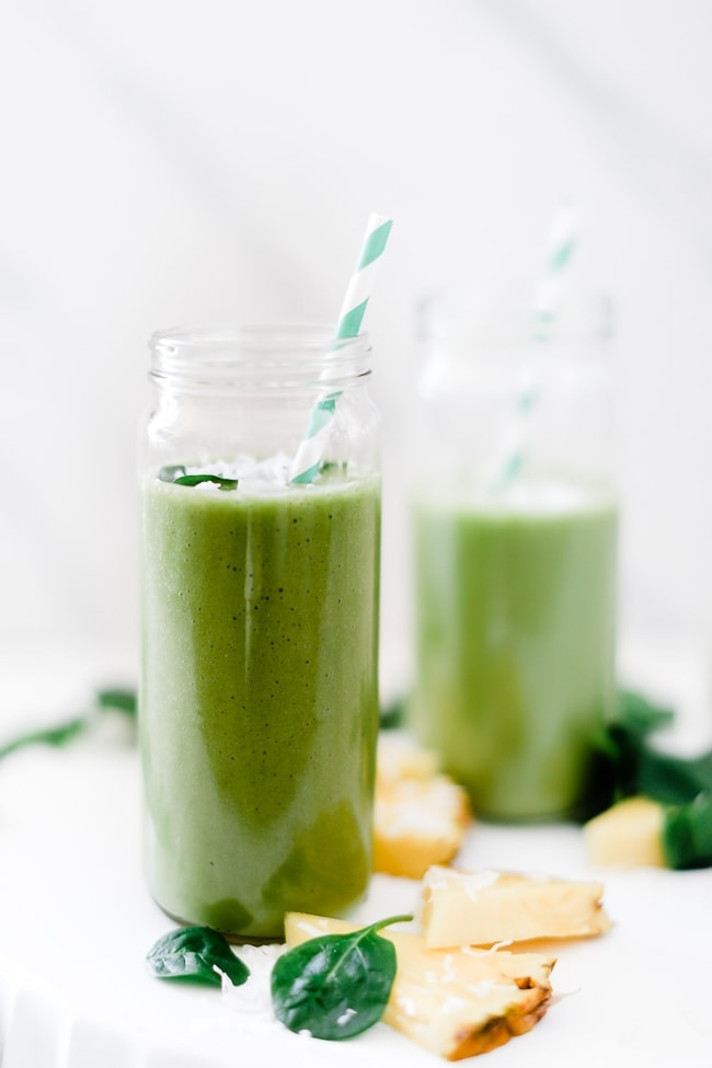 Proteína verde Pina colada smoothie num copo com uma palhinha.