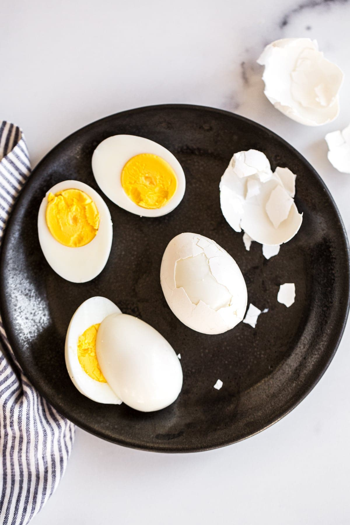 Ovos cozidos duros sendo descascados em um prato.